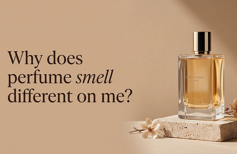Gold-capped perfume bottle on a stone plinth with pale flowers against a warm beige wall