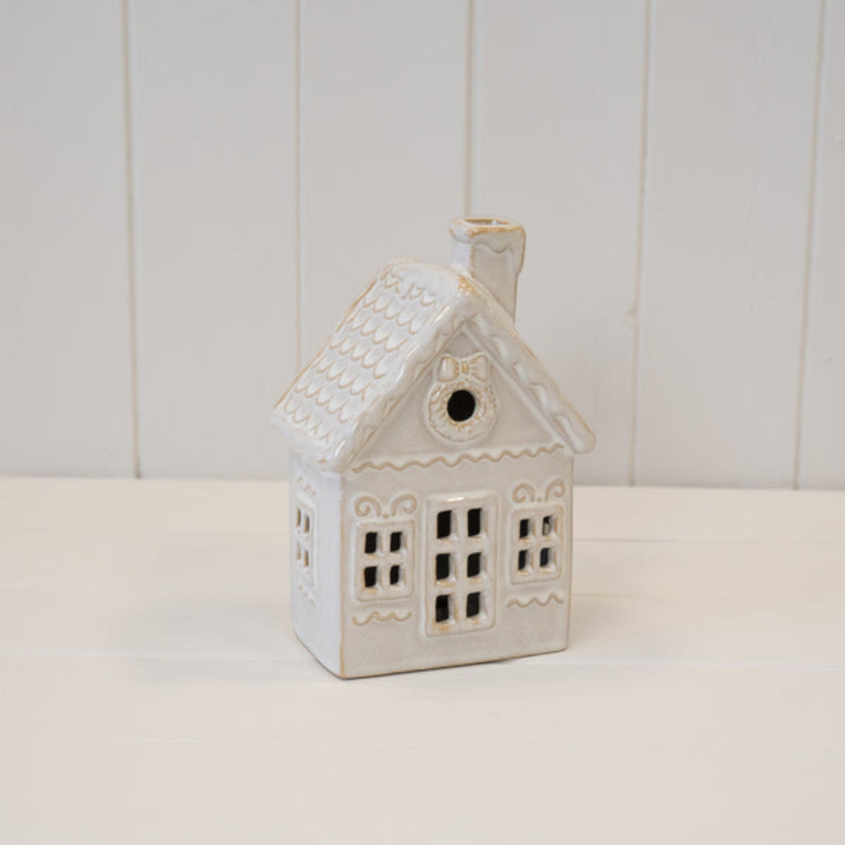 LED ceramic Christmas house on a white wooden shelf