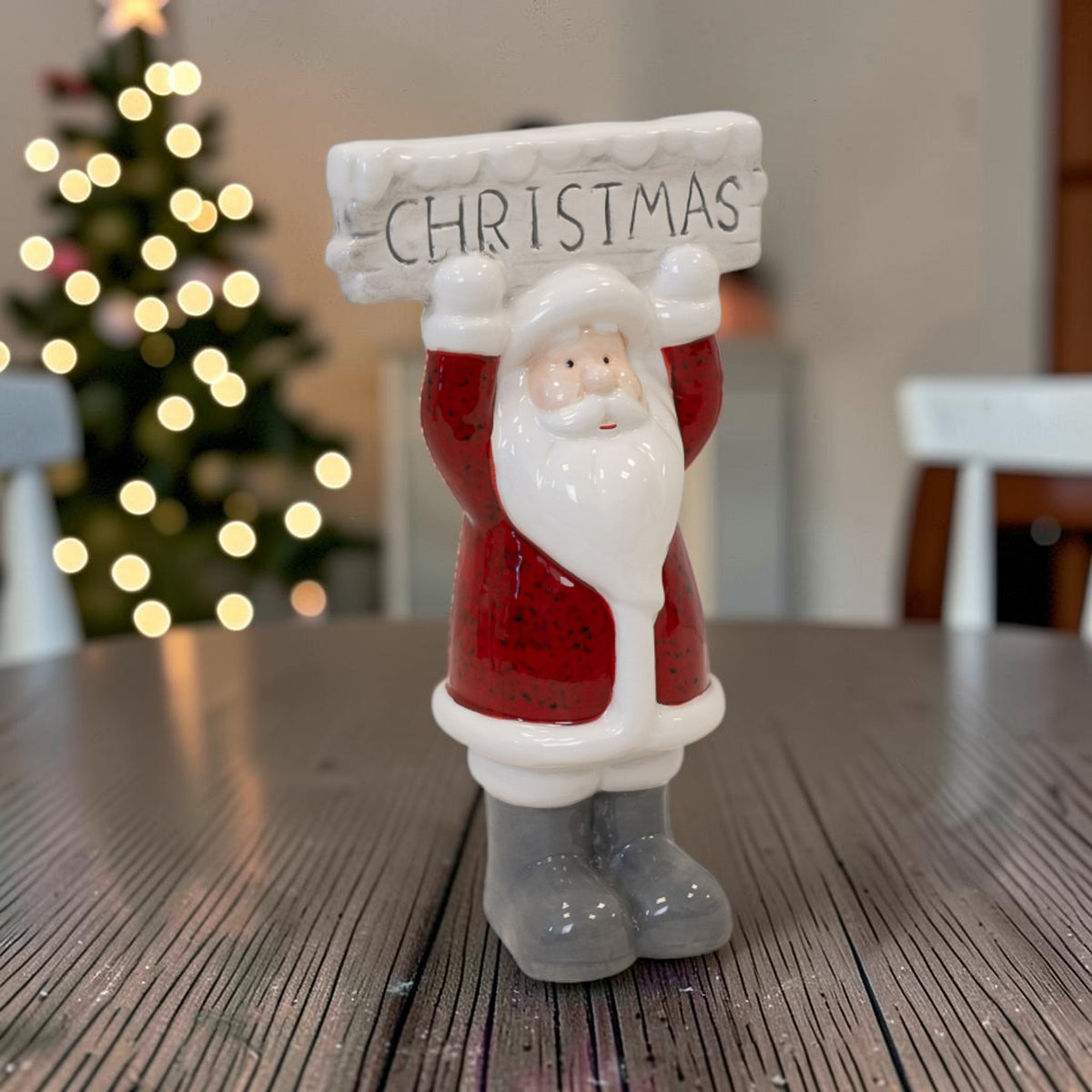 22cm ceramic Santa figurine with Christmas sign on a table in front of a lit tree