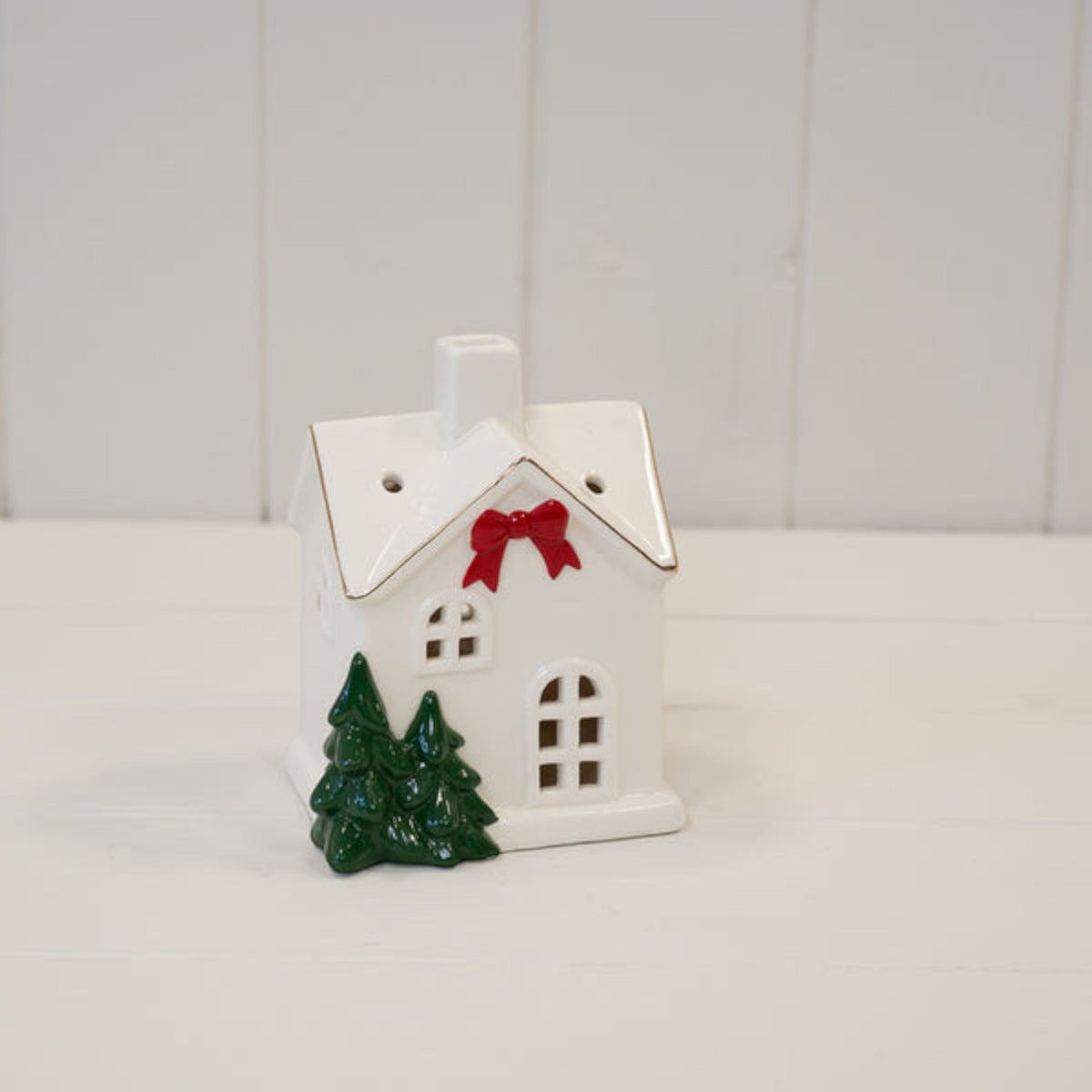 Medium white ceramic Christmas house on a white wooden shelf