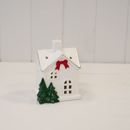 Medium white ceramic Christmas house on a white wooden shelf