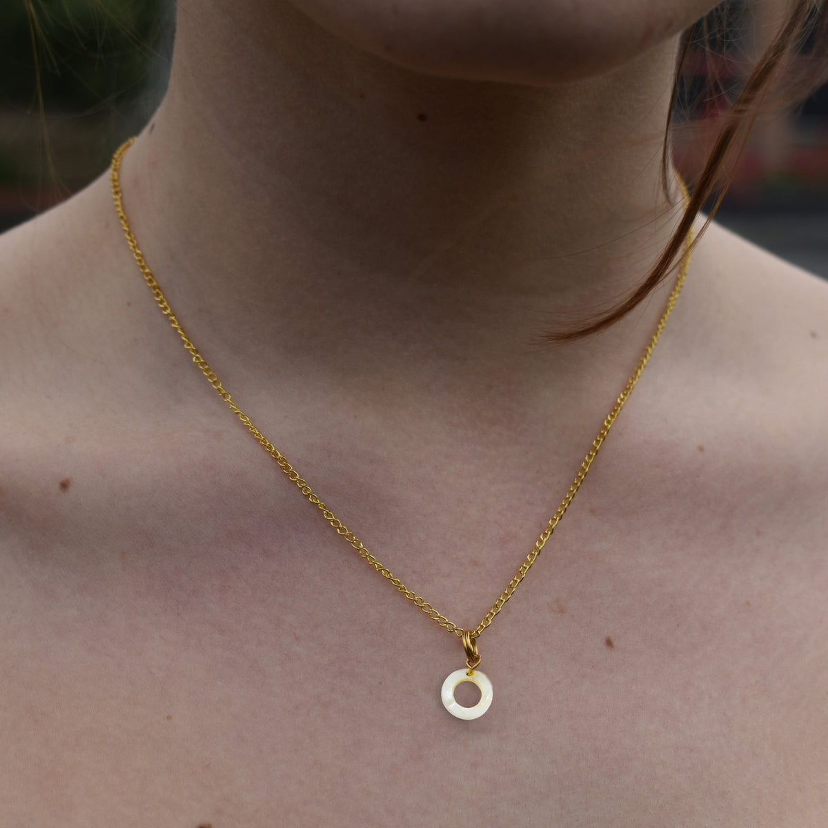 Mother of pearl circle pendant on a gold-plated chain, worn