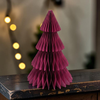 Claret red honeycomb paper Christmas tree on a wooden sideboard with fairy lights