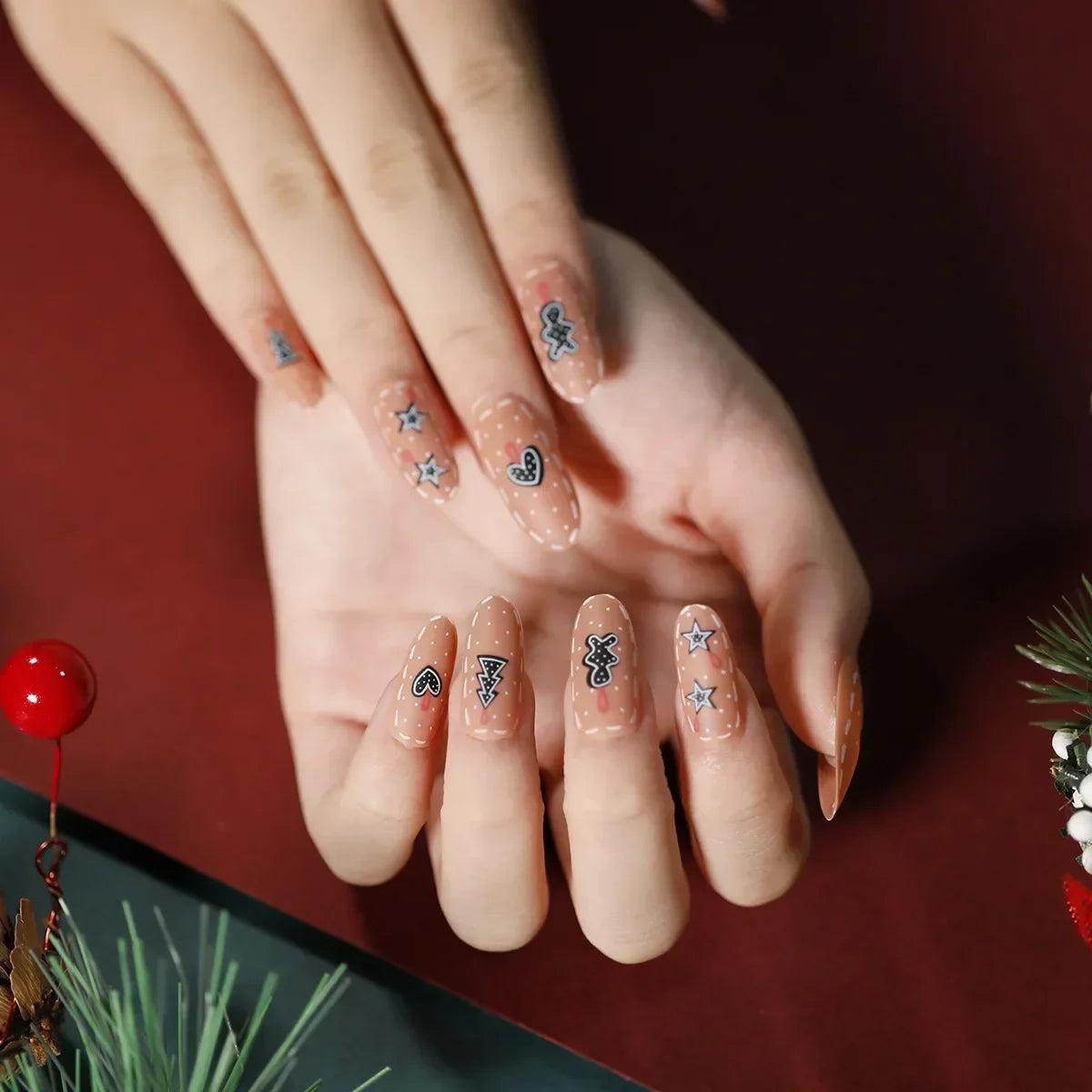 Nude Christmas press-on nails with small dark star and heart motifs