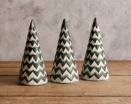 Three white and green zigzag wooden Christmas cone trees on a wooden table