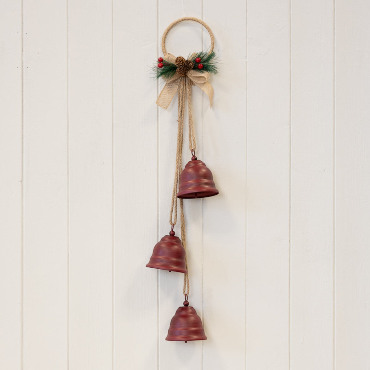 Hanging red Christmas bells decoration on a white panelled wall