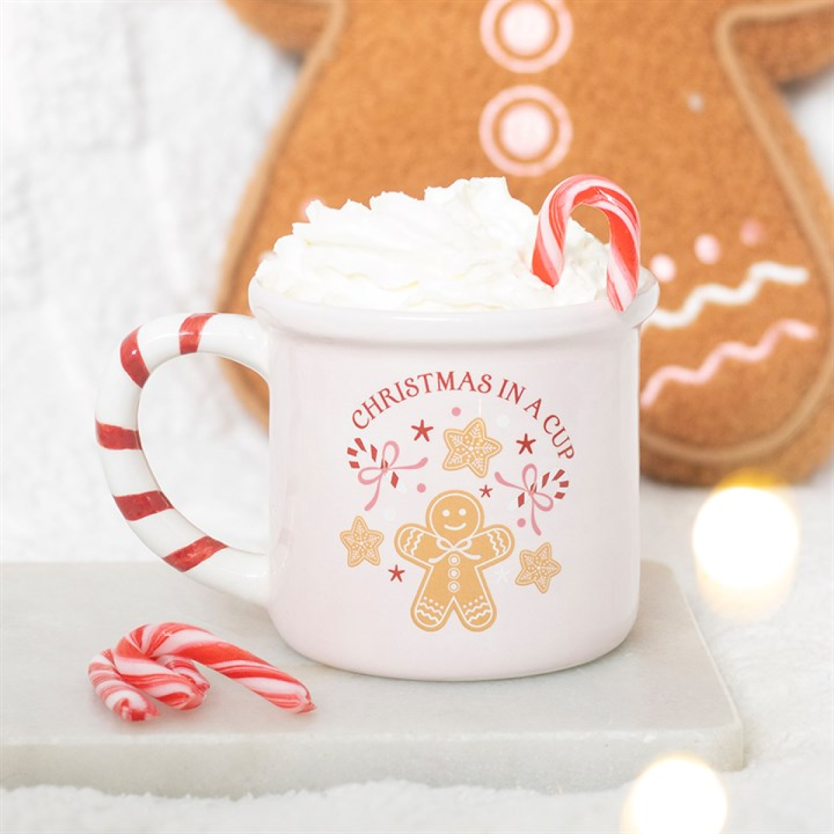 Pink Christmas in a Cup mug topped with whipped cream and a candy cane