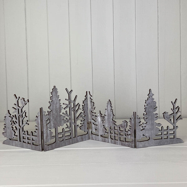 Grey wooden cut-out Christmas scene standing on a white shelf
