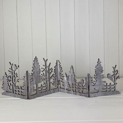 Grey wooden cut-out Christmas scene standing on a white shelf