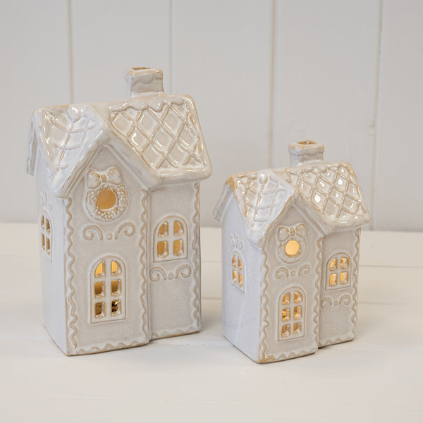 Two cream ceramic LED Christmas houses lit up side by side