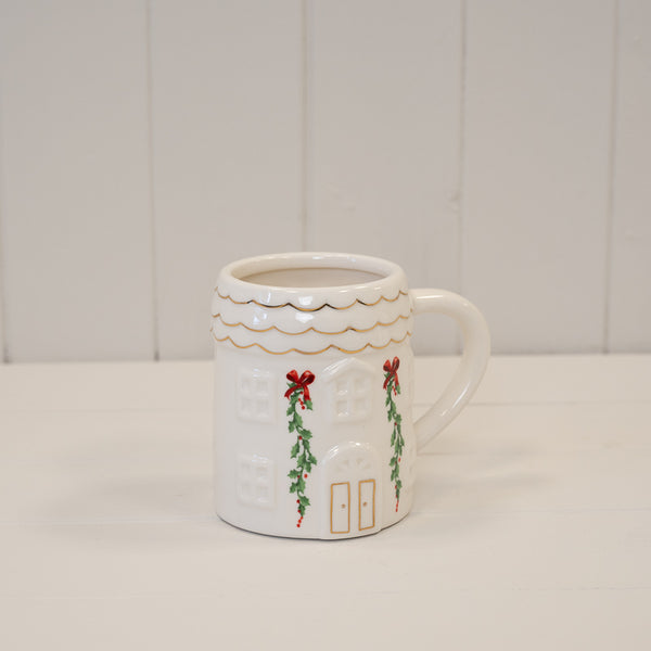 Christmas cottage mug with scalloped gold-trimmed rim on a white shelf