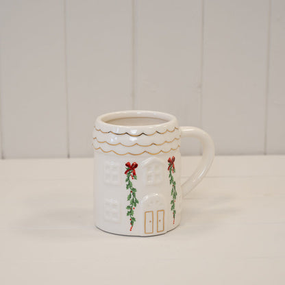 Christmas cottage mug with scalloped gold-trimmed rim on a white shelf